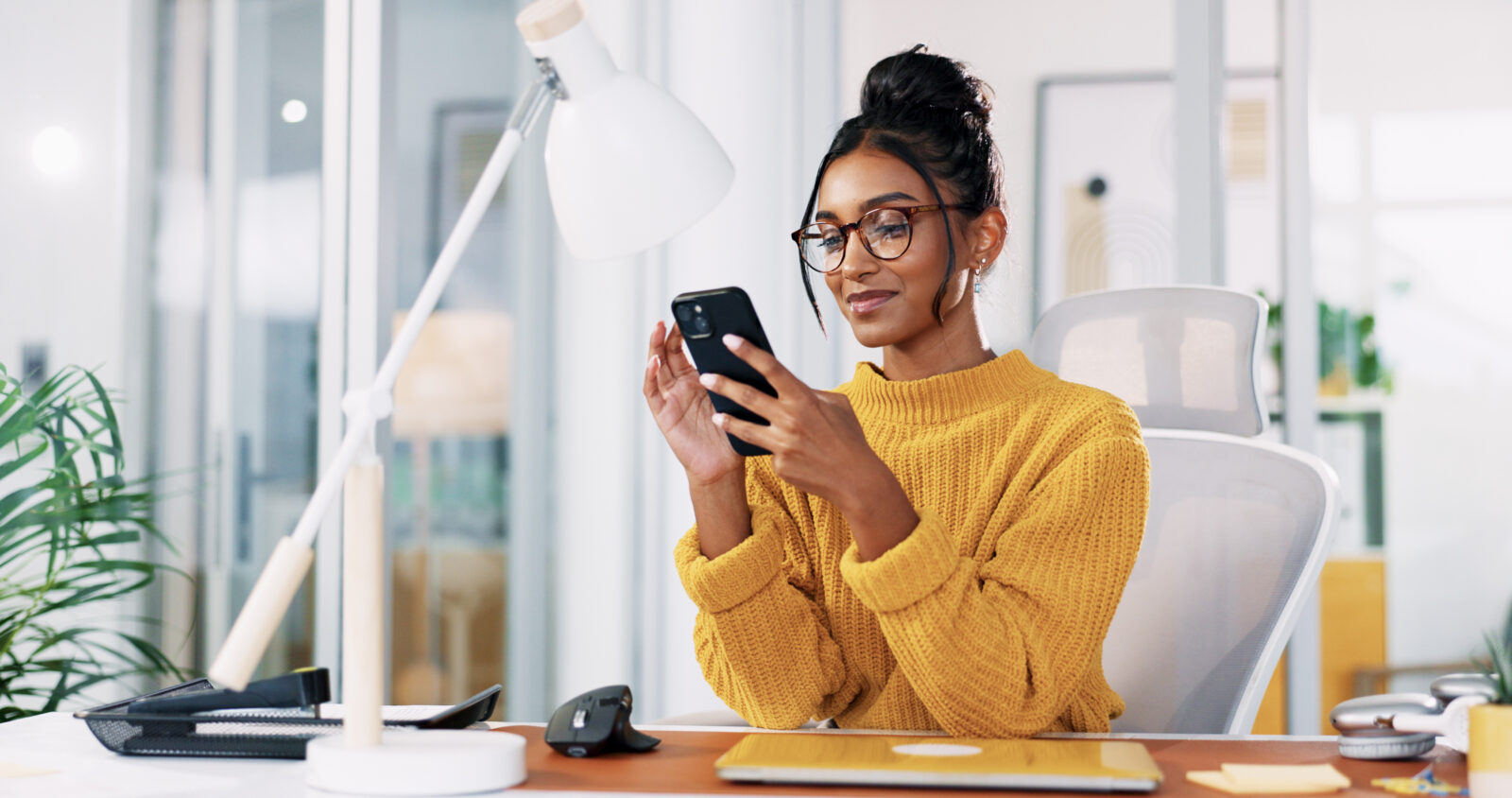 Eine Frau sitzt auf der Arbeit am Handy - Symbolbild