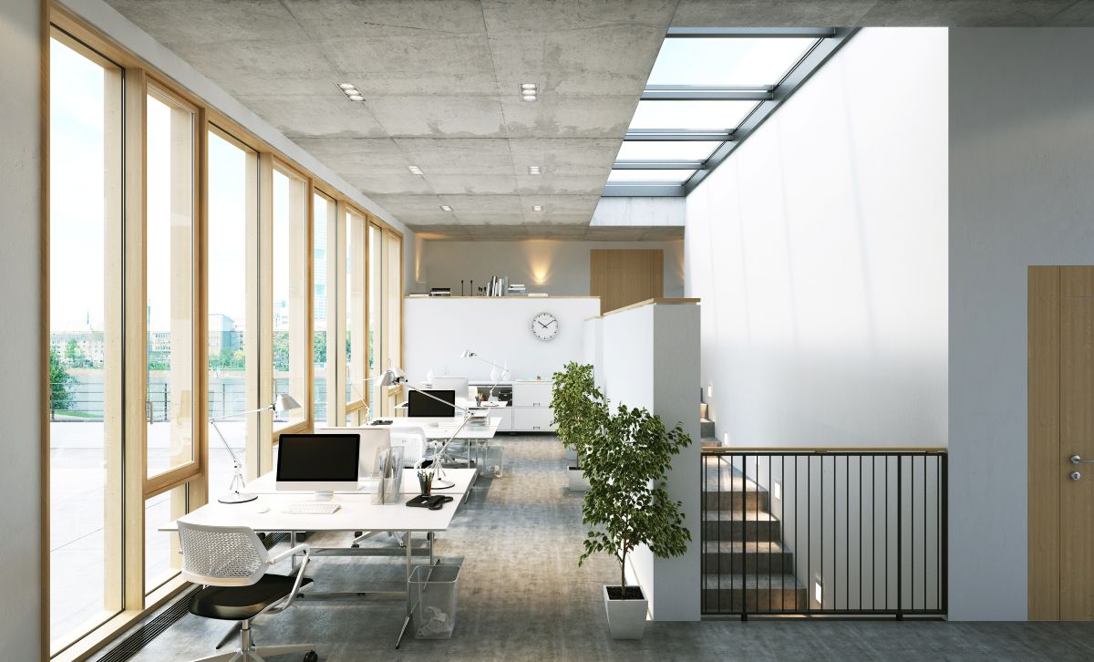 Lichtkonzept Büro: Ein lichtdurchflutetes, modernes Büro mit Deckenfenstern und bodentiefen Fenstern.