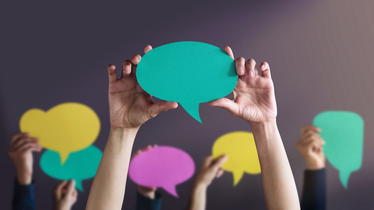 Klarheit statt Chaos: Eine Gruppe von Menschen hält mehrere Sprechblasen in die Luft.